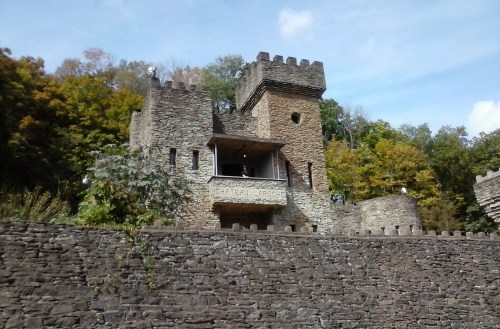 A stone castle with towers, surrounded by trees, set against a blue sky.