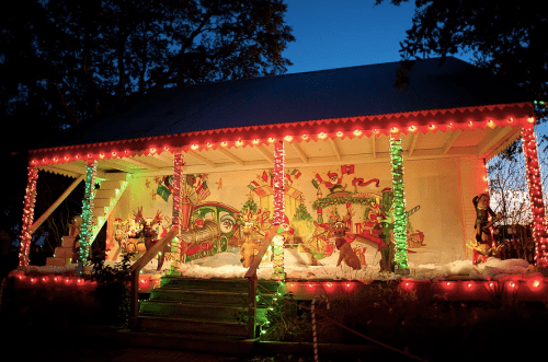 A festive house decorated with colorful lights and holiday decorations, set against a twilight sky.