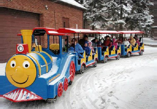 A colorful train ride with children and adults, traveling through a snowy landscape.