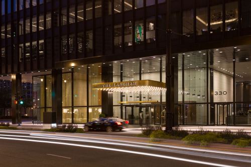 The Langham hotel entrance at night, featuring modern architecture and illuminated signage.