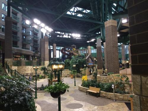 Indoor water park with slides, greenery, and stone pathways, featuring a spacious, well-lit atrium.
