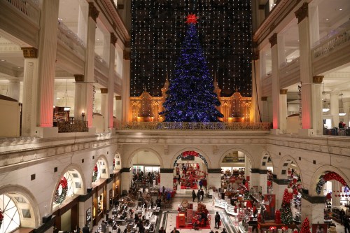 A grand indoor space decorated for the holidays, featuring a large blue Christmas tree and festive lights.