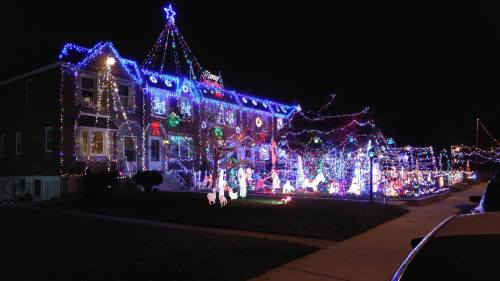 A brightly lit house decorated with colorful Christmas lights and festive displays, glowing in the night.