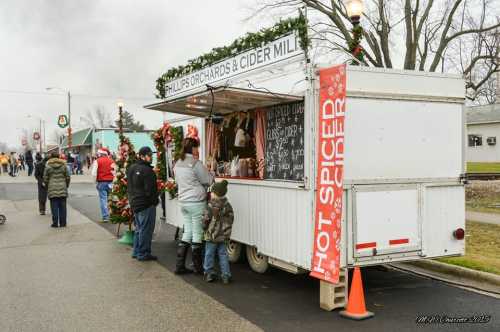 A festive cider stand with holiday decorations, serving hot spiced cider to customers on a chilly day.