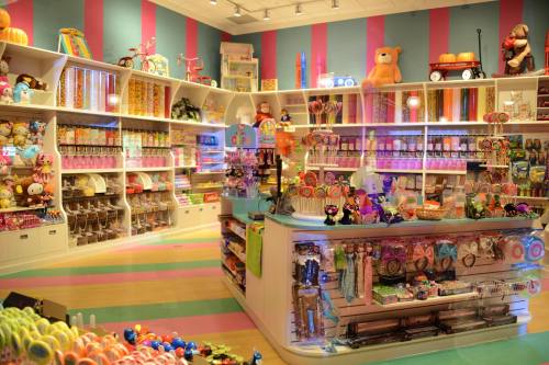 A colorful candy store filled with toys, sweets, and vibrant decorations on shelves and displays.