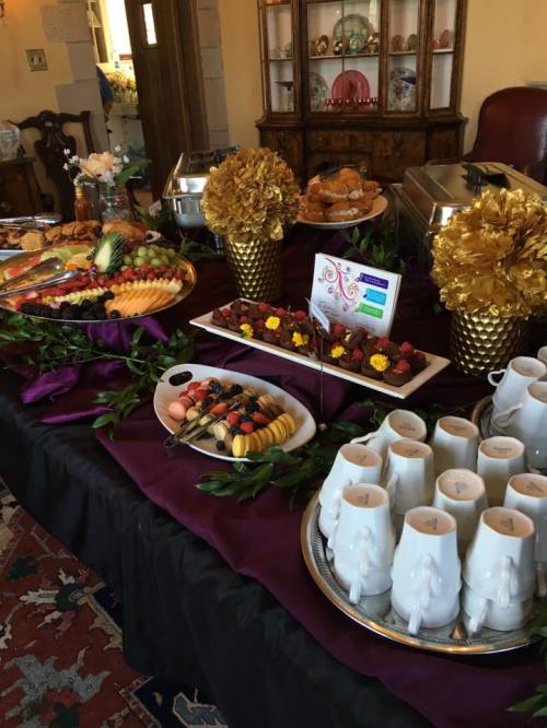 A beautifully arranged buffet table with fruit platters, pastries, and decorative floral centerpieces.