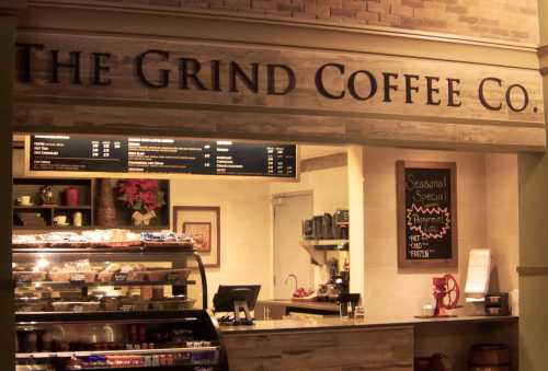 A coffee shop counter with a menu board, pastries display, and a seasonal special sign. Warm, inviting atmosphere.