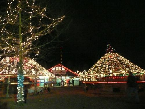 Colorful holiday lights illuminate festive structures at night, creating a cheerful winter scene.