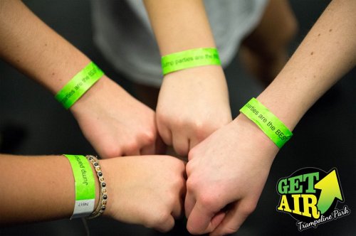 Four hands wearing green wristbands with the text "Jump parties are the best!" at Get Air Trampoline Park.