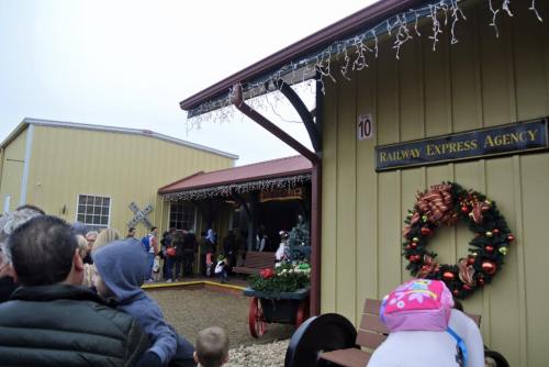 A festive railway express agency with holiday decorations, surrounded by a crowd of people enjoying the scene.