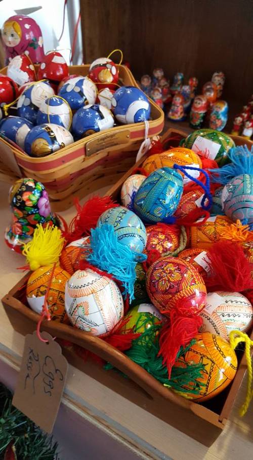 Colorful decorative eggs with vibrant tassels and patterns, displayed in baskets on a shelf.
