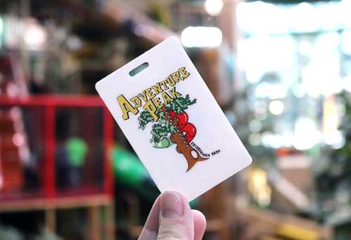 A hand holds an "Adventure Park" card featuring colorful graphics and a playful design.