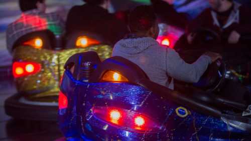 A group of people enjoying bumper cars at an amusement park, with colorful lights and a festive atmosphere.