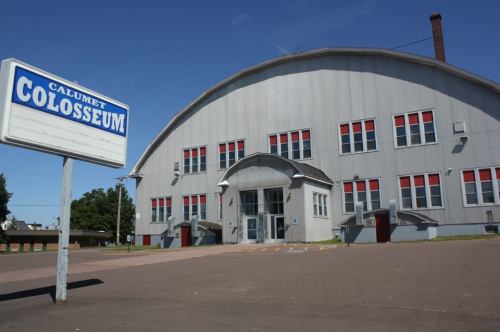 Exterior view of the Calumet Colosseum, a large gray building with red windows and a sign in front.
