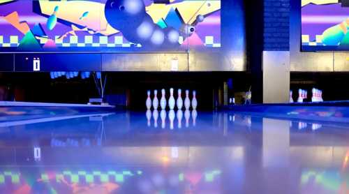 A bowling alley with colorful graphics, featuring a row of pins and a shiny, reflective lane.