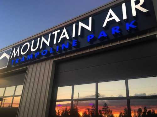 Sign for Mountain Air Trampoline Park, reflecting a colorful sunset in the windows.