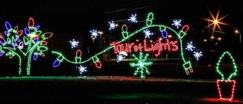 Colorful holiday lights display featuring trees, snowflakes, and the words "Trail of Lights" against a dark background.