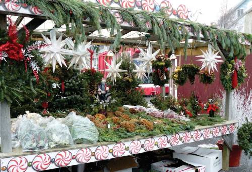 A festive market stall decorated with holiday greenery, pinecones, and stars, surrounded by candy cane motifs.
