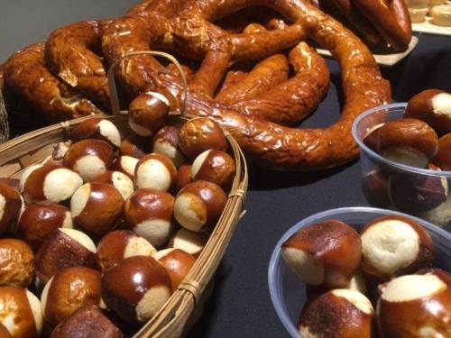 A display of pretzel-shaped bread and round, brown-and-white snacks in baskets on a black tablecloth.