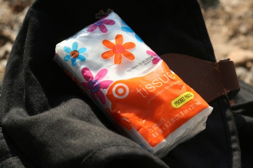 A pack of colorful floral tissues resting on a black bag.