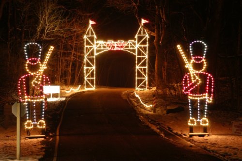 A festive entrance with illuminated toy soldiers and a lighted archway, set in a snowy, dark landscape.
