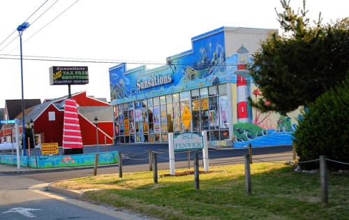 Colorful storefront of "Fun Stations" with murals, surrounded by greenery and a striped lighthouse decoration.