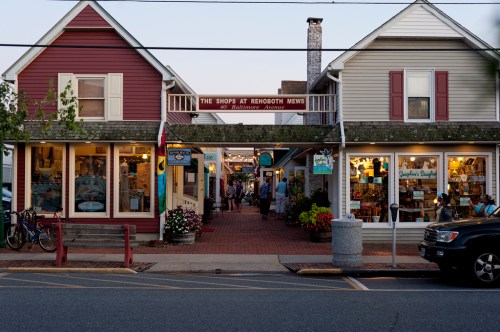 A charming street view of shops in Rehoboth, with colorful storefronts and people strolling along the walkway.