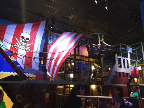Colorful indoor play area featuring pirate-themed decorations, climbing structures, and a large striped flag.