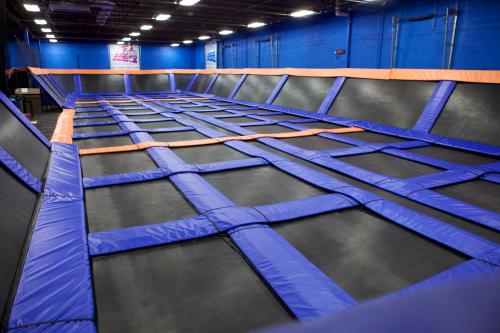 A spacious indoor trampoline park with multiple interconnected trampolines and blue walls.
