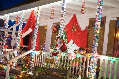 A festive porch decorated with colorful lights, red drapes, and holiday ornaments for the Christmas season.
