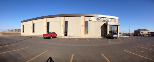 Exterior view of a Sky Zone trampoline park building with a red truck parked in front on a clear day.