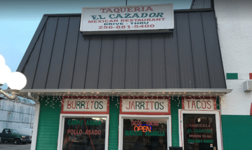 Exterior of Taqueria El Cazador, a Mexican restaurant with signs for burritos, tacos, and open hours.