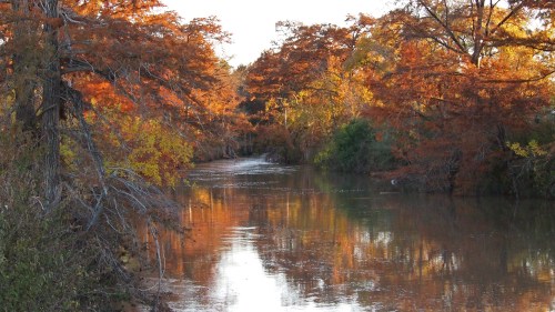 A serene river surrounded by vibrant autumn foliage reflecting in the water.