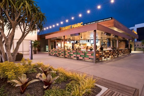 A cozy outdoor dining area at Saint Marc, featuring string lights and lush greenery in the evening.