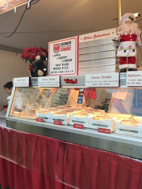 A booth displaying various strudel options, including apple, cherry, and cheese, with festive decorations.