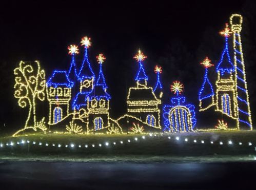 Colorful holiday lights depict a whimsical castle scene with towers and trees against a dark night sky.