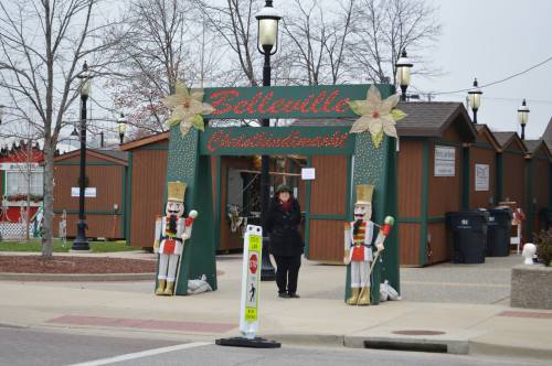 Entrance to a festive market with nutcracker decorations and wooden stalls, set against a gray sky.