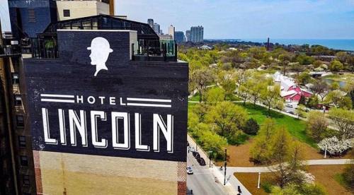 Aerial view of Hotel Lincoln sign with green park and city skyline in the background.