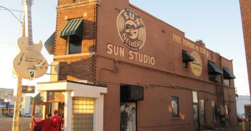 Exterior of Sun Studio, a historic music venue, featuring a large guitar sign and iconic logo on the brick building.