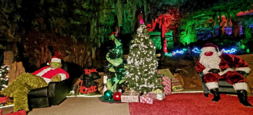 A festive scene featuring the Grinch, a Christmas tree, and Santa in a colorful cave setting with holiday decorations.