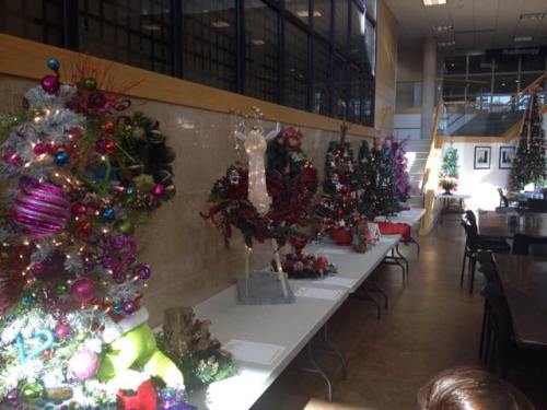 A festive display of decorated Christmas trees and holiday decorations in a bright indoor space.