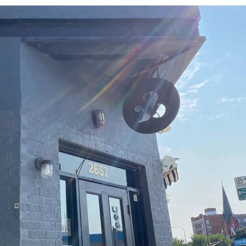 A building exterior featuring a round sign, door, and address number 2657, with a clear blue sky in the background.