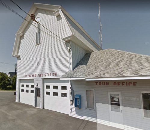 Exterior of St. Francis Fire Station, featuring a white building with a sloped roof and a sign for the town office.