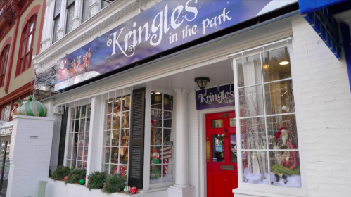 A festive storefront with "Kringles in the Park" sign, decorated windows, and holiday decorations.