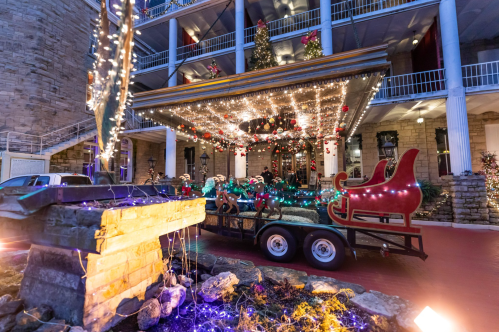 A festive scene featuring a decorated sleigh on a trailer, surrounded by colorful lights and holiday decorations.