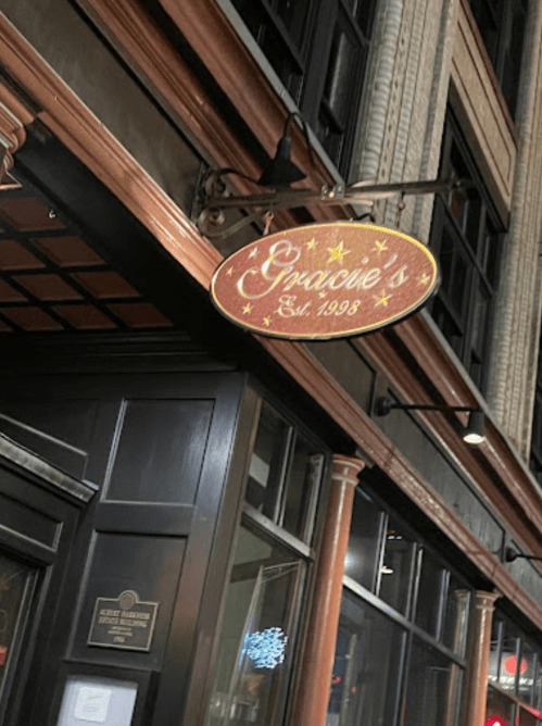 Sign for Gracie's, established in 1993, illuminated at night on a building exterior.