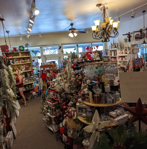 A festive shop filled with holiday decorations, ornaments, and gifts, with a customer browsing in the background.