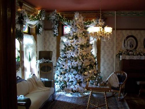 A cozy room decorated for the holidays, featuring a large white Christmas tree and festive garlands.