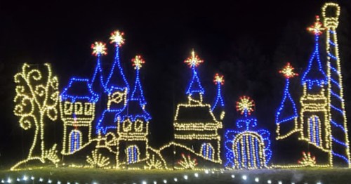 Colorful holiday lights depict a whimsical castle with towers and stars against a dark night sky.