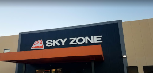 Exterior of a Sky Zone trampoline park building with a prominent logo and orange awning.